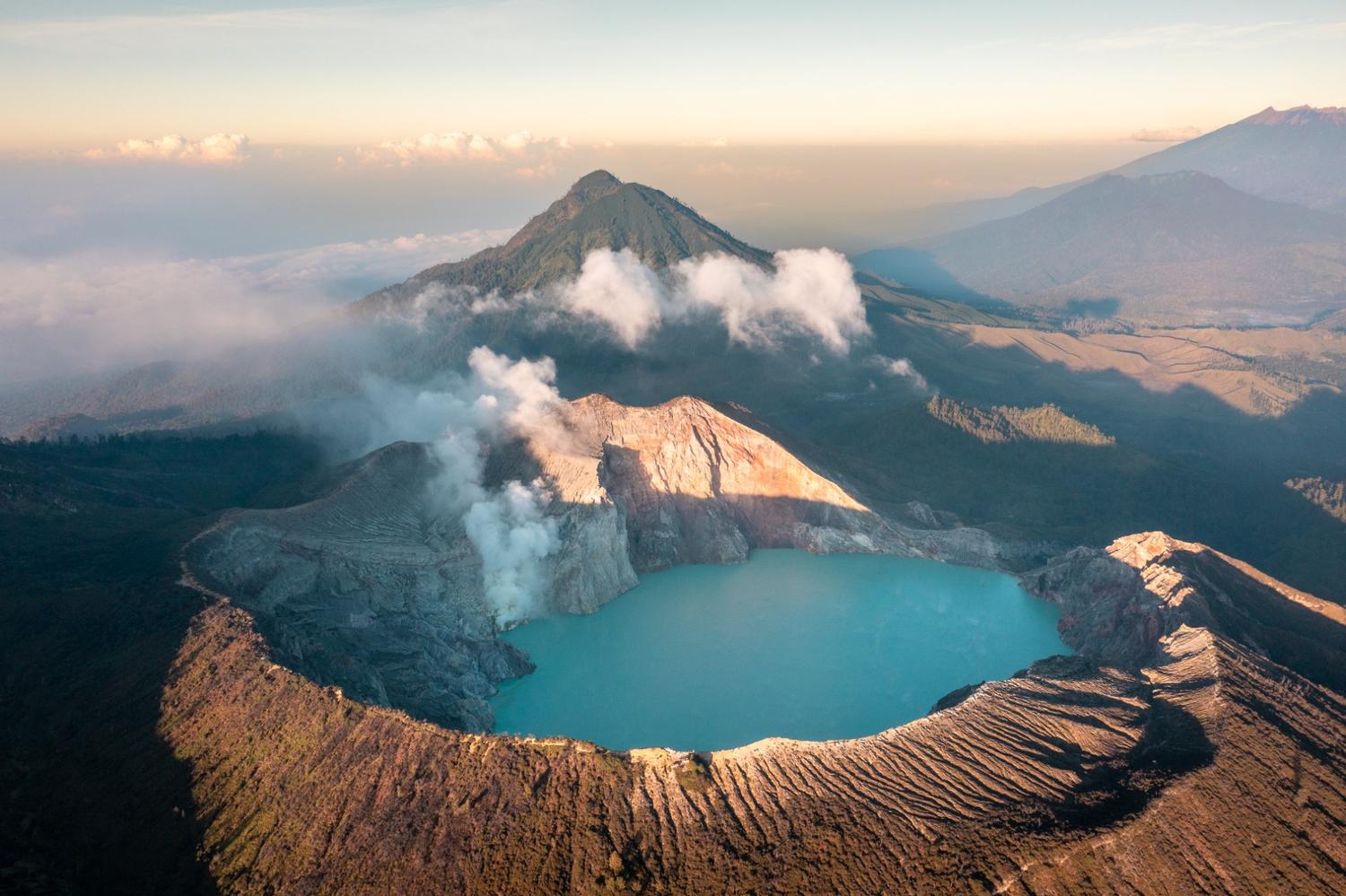 Aerial view of Kawah Ijen crater with turquoise lake, surrounded by mountains in East Java, Indonesia.