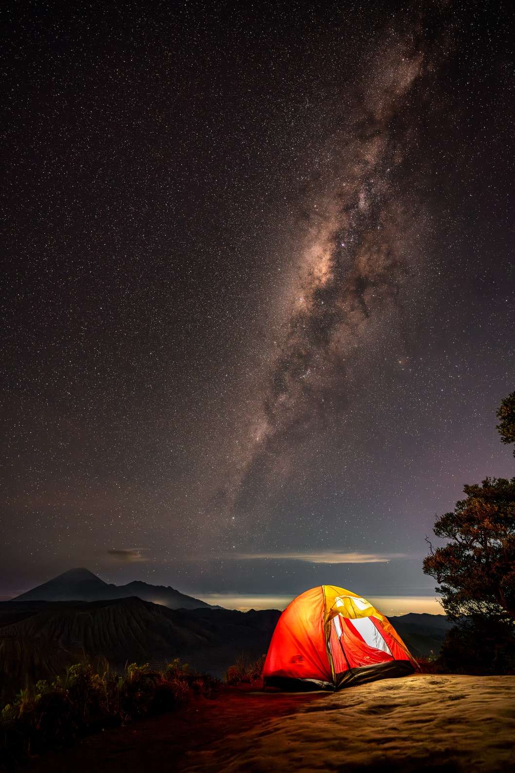 A tent under the starry night sky with the Milky Way over Mount Bromo, East Java.