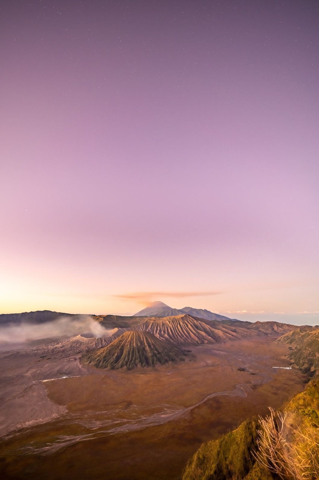 Sunset view of Mount Bromo and surrounding peaks, glowing in warm golden light.